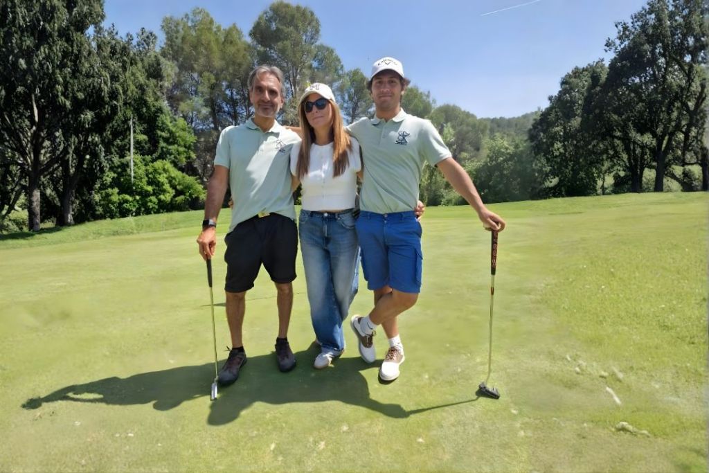 Dos jugadores y una jugadora posan en el campo de golf
